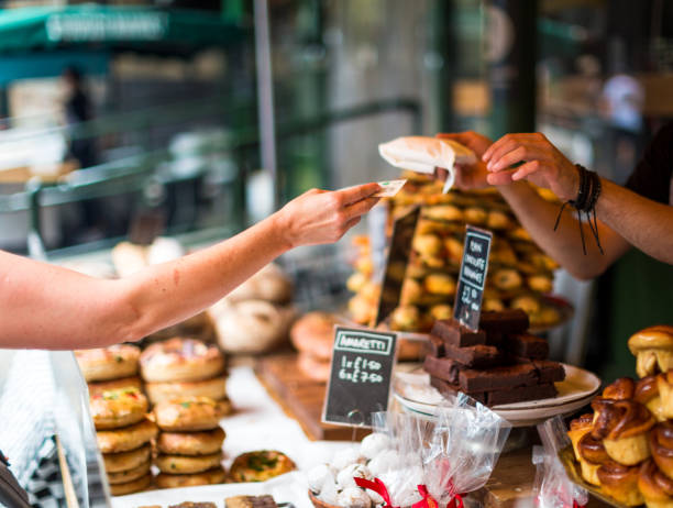 cliente pagar pasteles dulces utilizando dinero en efectivo en el mercado de alimentos - retail london england uk people fotografías e imágenes de stock