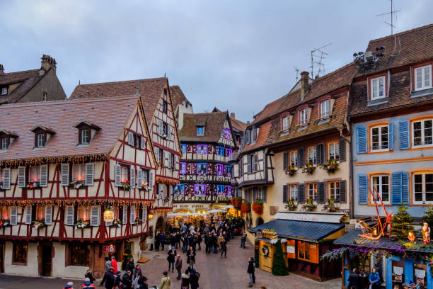 Beautiful half-timbered buildings decorated for Christmas in the old town of Colmar, a city located in the cultural and historical region of Alsace, eastern France, renowned for its well-preserved historic centre. People strolling.