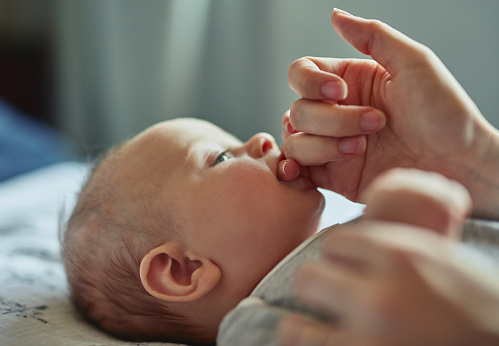 Shot of an adorable baby boy sucking on his mother's finger