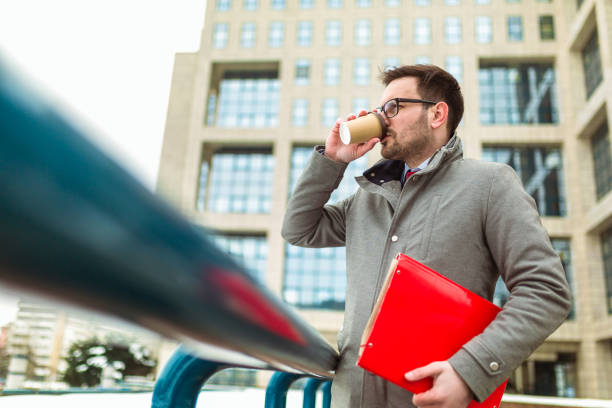 istock Confident young man in glasses drinking coffee outdoors 1011839864