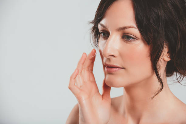 Studio shot of an attractive woman feeling her skin against a gray background