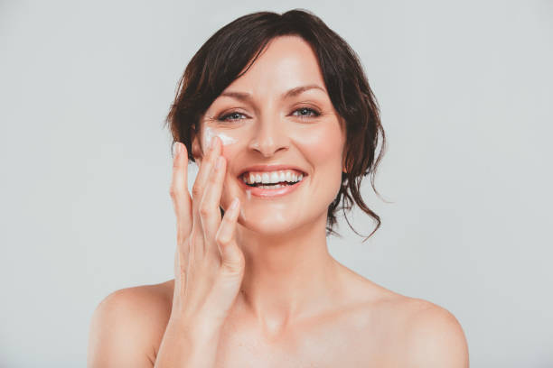 No under eye circles for me Studio shot of an attractive woman applying moisturizer to her face against a gray background anti aging stock pictures, royalty-free photos & images