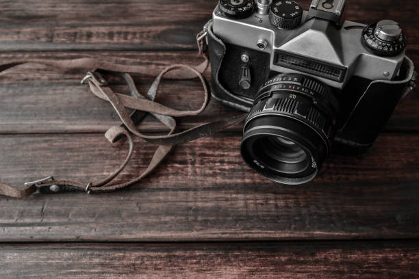 istock Old photo camera on a wooden background 1011848118