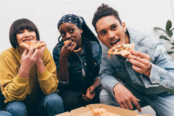 istock smiling multicultural group of friends eating pizza and watching match 1011849662