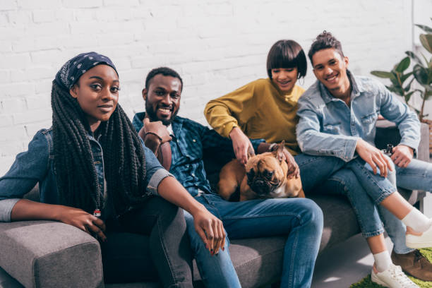 istock group of young multiethnic friends sitting on couch with dog 1011849882