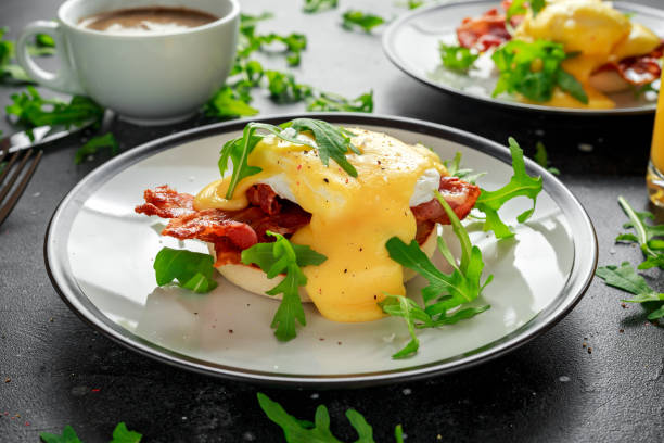 istock Eggs Benedict on english muffin with crispy bacon, wild rocket salad and hollandaise sauce 1011853242