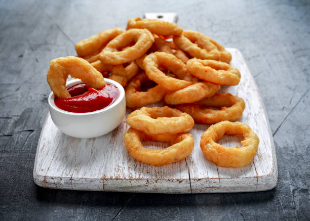 istock Fried Onion Rings with Ketchup on white cutting board 1011856054