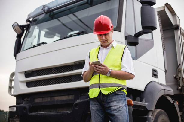 vrachtwagenchauffeur met behulp van een mobiele app - chauffeur beroep stockfoto's en -beelden