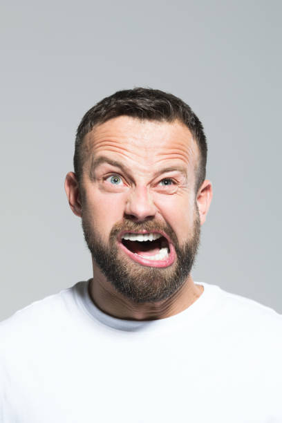 istock Headshot of angry bearded young man, grey background 1011870844