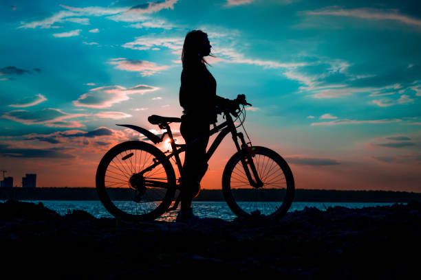 Silhouette of a girl with a bicycle on the lake