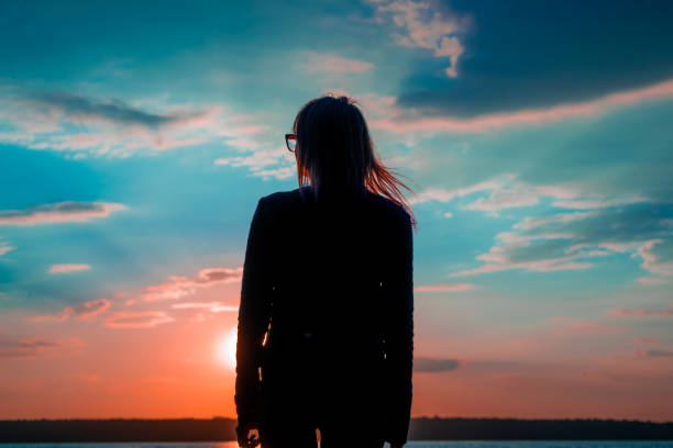 istock Young woman watching sunset at the lake 1011871064