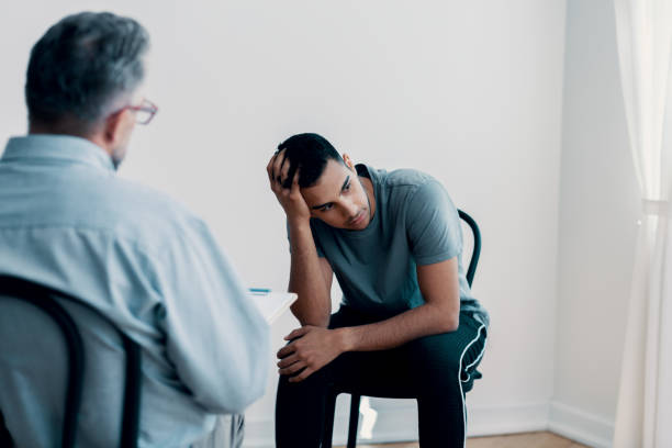 Depressed teenager looking away while talking to his therapist Depressed teenager looking away while talking to his therapist substance abuse stock pictures, royalty-free photos & images