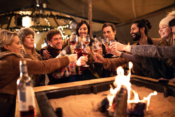 Friends Making a Celebratory Toast Medium group of mid adult friends sitting inside of a teepee next to a fire pit. The friends are talking, laughing and enjoying a glass of rose wine. english spoken stock pictures, royalty-free photos & images