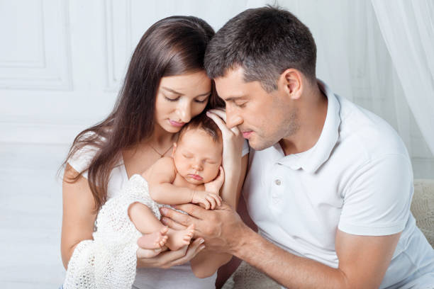 Woman and man holding a newborn. Mom, dad and baby. Close-up. Portrait of  smiling family with newborn on the hands.  Happy family concept stock photo
