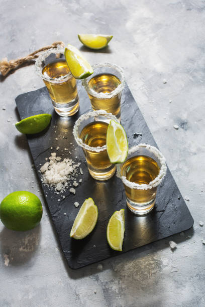 istock Mexican gold tequila with lime and salt on black stone background 1011899388