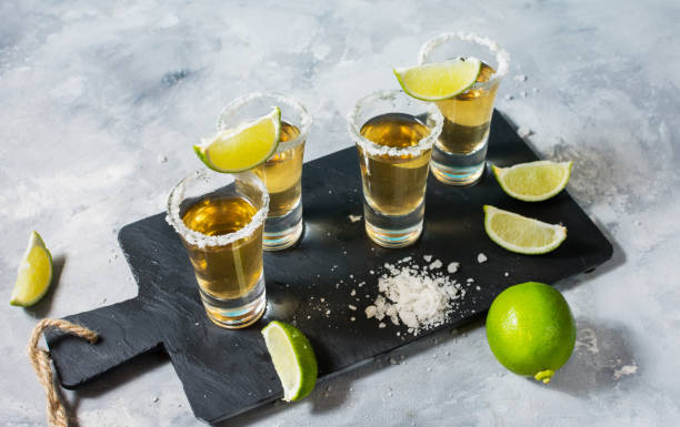 istock Mexican gold tequila with lime and salt on black stone background 1011899532