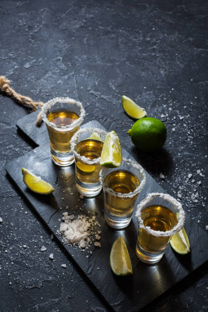 istock Mexican gold tequila with lime and salt on black stone background. 1011899558
