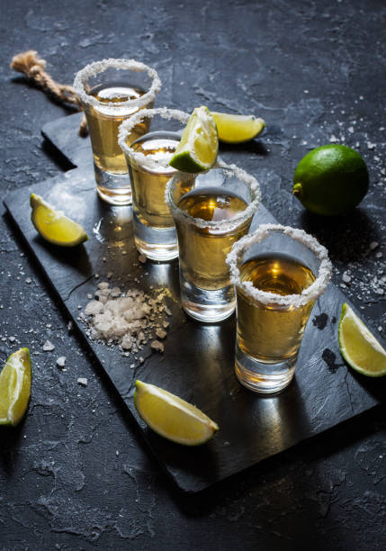 istock Mexican gold tequila with lime and salt on black stone background. 1011899648