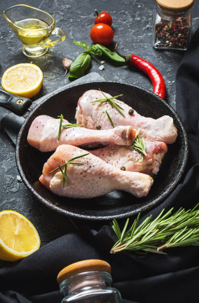 istock Raw uncooked chicken legs, drumsticks on stone board, meat with ingredients for cooking 1011899866