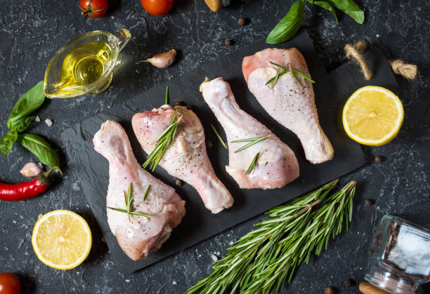 istock Raw uncooked chicken legs, drumsticks on stone board, meat with ingredients for cooking 1011899974