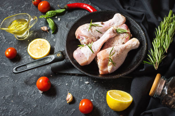 istock Raw uncooked chicken legs, drumsticks on stone board, meat with ingredients for cooking 1011900152