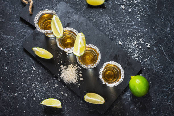 istock Mexican gold tequila with lime and salt on black stone background 1011900186
