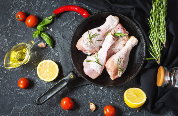 istock Raw uncooked chicken legs, drumsticks on stone board, meat with ingredients for cooking 1011900296