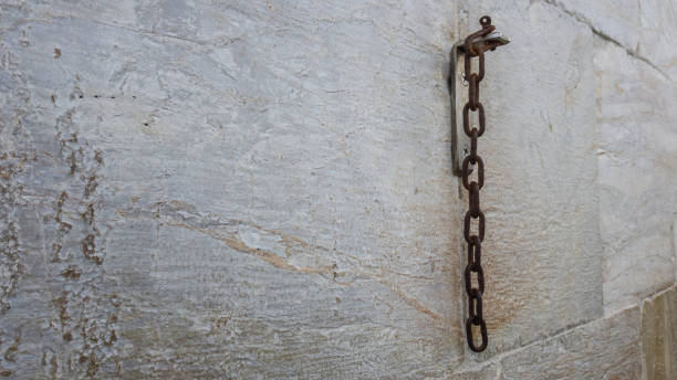 istock A piece of rusty chain hangs on a stone wall 1011900314