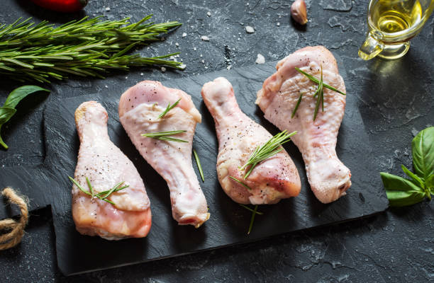 istock Raw uncooked chicken legs, drumsticks on stone board, meat with ingredients for cooking. 1011900384