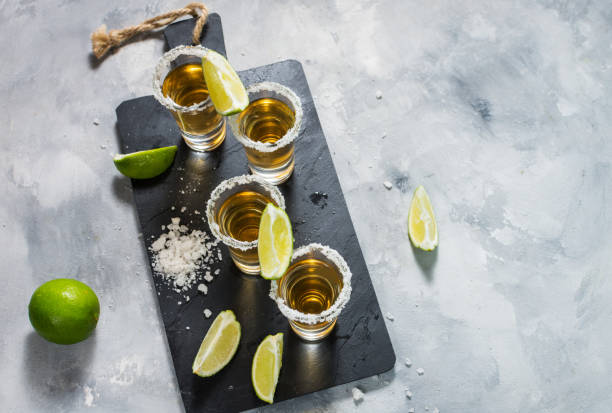 istock Mexican gold tequila with lime and salt on black stone background. Top view 1011900484