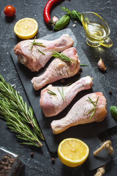 istock Raw uncooked chicken legs, drumsticks on stone board, meat with ingredients for cooking. 1011905096