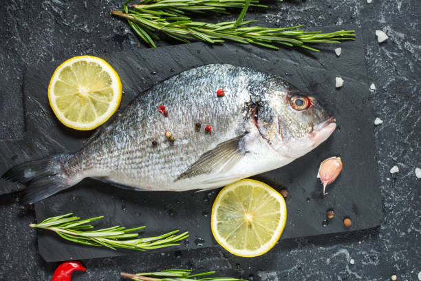 istock Raw fresh dorado with lemon on dark stone background. 1011905170