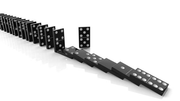 istock Black domino tiles falling in a row with some standing, isolated on white 1011906276