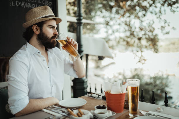 istock Bearded man drinking beer in a restaurant and enjoying the view from a balcony 1011911468