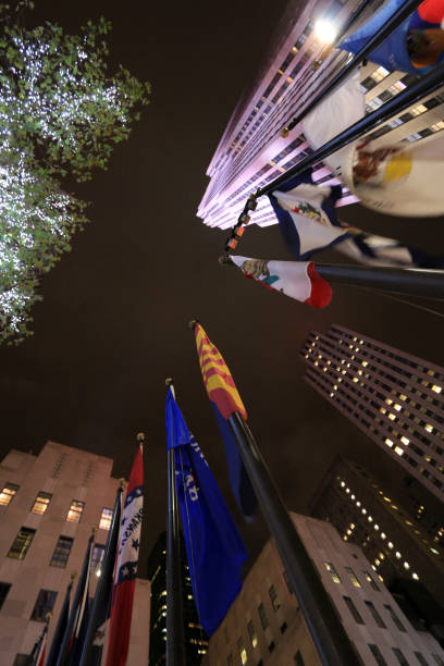 Flags of all US states at the Rockefeller Center in Manhattan, New York City Manhattan, New York City, USA, November 1st, 2014. Night shot showing flags of different US states on flagpoles. The illuminated Rockefeller Center is in the background. rockefeller ice rink stock pictures, royalty-free photos & images