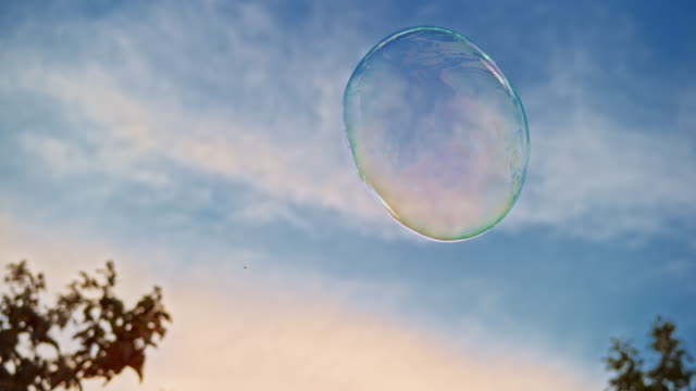 SLO MO Large bubble floating in the air outside with blue sky in the background