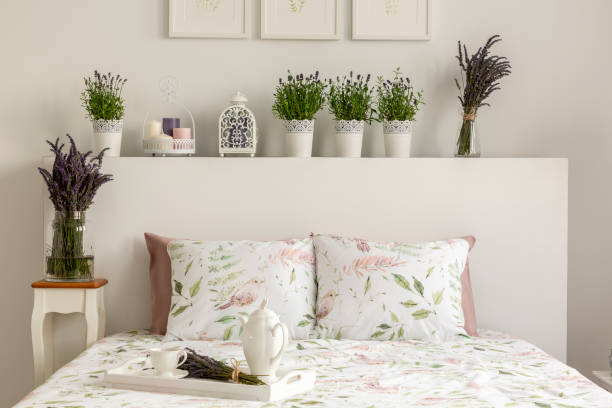 intérieur de lavande chambre avec un lit, oreillers, plateau en bois avec pot, des fleurs et des décorations. vraie photo - bedding cushion purple pillow photos et images de collection