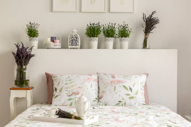 interior de lavanda quarto com uma cama, almofadas, bandeja de madeira com pote, flores e decorações. foto real - bedding cushion purple pillow - fotografias e filmes do acervo