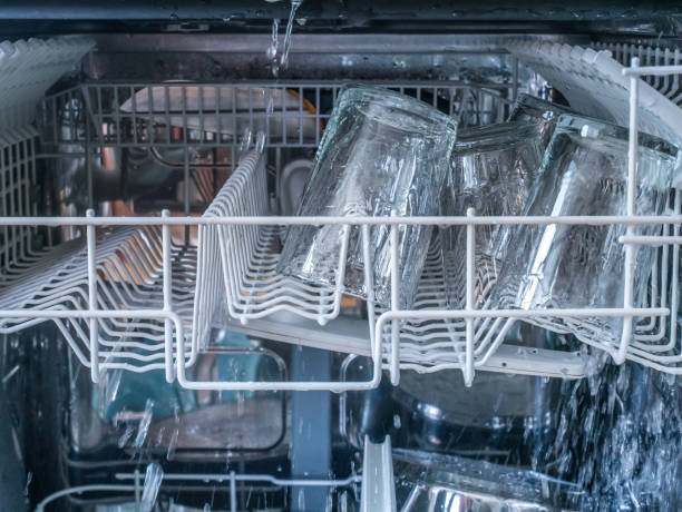 istock Dishwasher machine open with water spraying glass. 1011922784