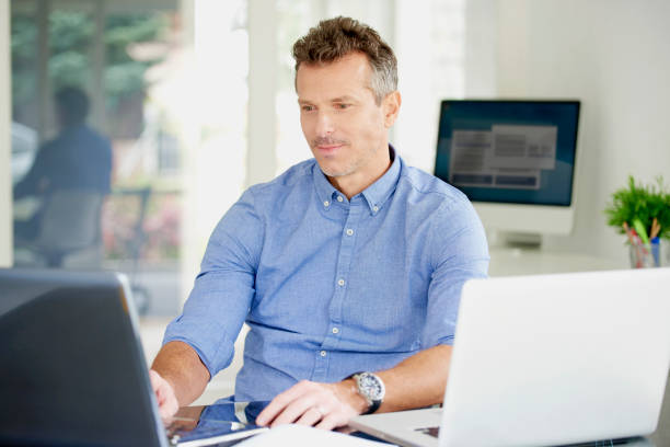 istock Middle aged businessman working on notebooks at the office 1011923122