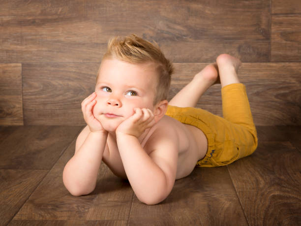 istock blond boy with hands on chin lying on wooden floor 1011929826