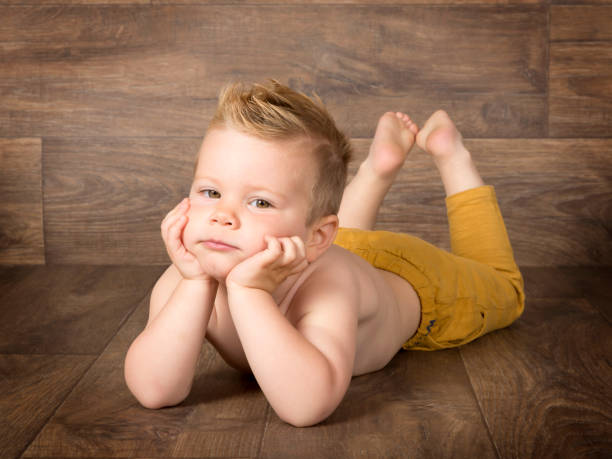 istock blond boy with hands on chin lying on wooden floor 1011929866