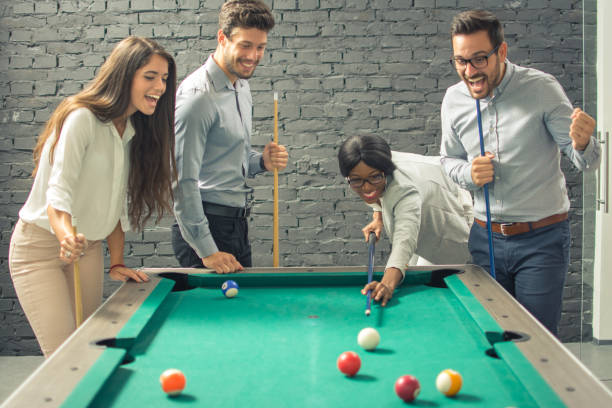 istock Young cheerful businesspeople playing billiards at office after work. 1011935432