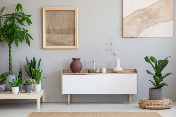 posters on grey wall above white cupboard in living room interior with plants and pouf. real photo - construction platform wood nature contemporary imagens e fotografias de stock