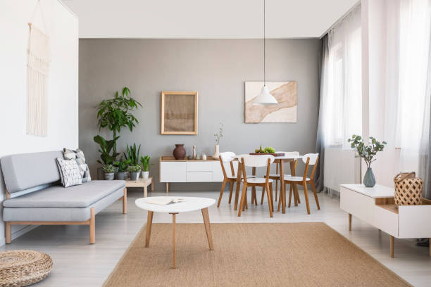white table on brown carpet in living room interior with grey sofa and posters. real photo - construction platform wood nature contemporary imagens e fotografias de stock