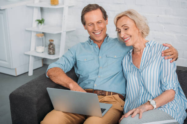 istock smiling senior couple using laptop while sitting together at home 1011944280