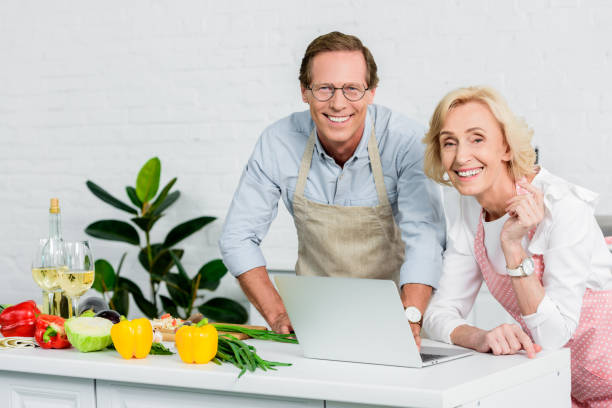 istock senior couple cooking and using laptop for recipes at kitchen 1011950276