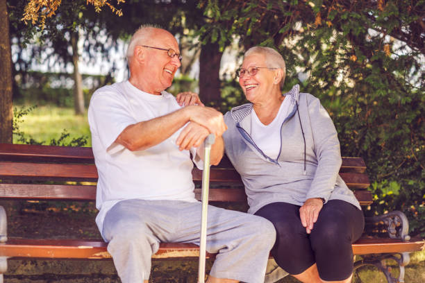 istock Smiling senior couple sitting on a park bench 1011950486