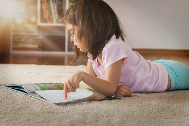 Cute girl reading a book on the floor stock photo