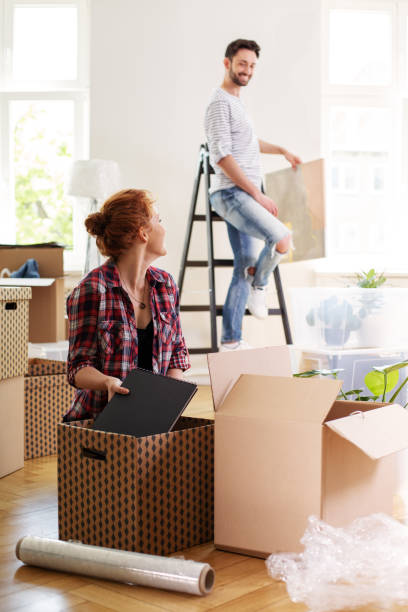 istock Woman packing stuff into boxes while moving out with husband to other house 1011954036